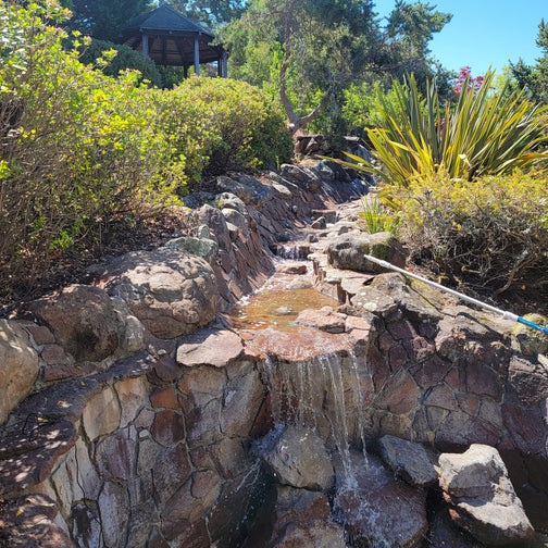 Rocky garden with a small waterfall and greenery